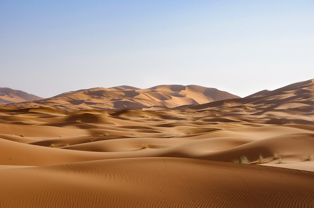 Desert dunes and hills under a clear sky